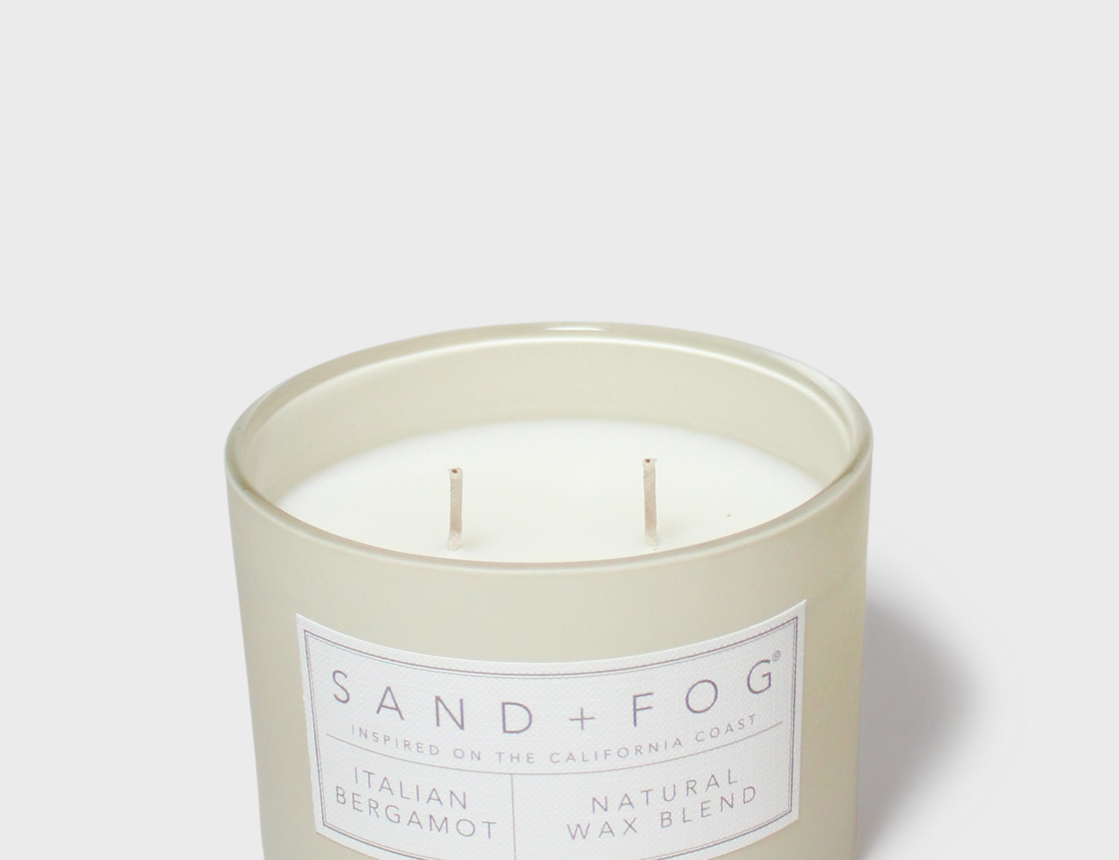 Scented candle in pale cream glass jar with two wicks and 'Bergamot' label