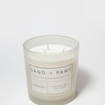 21 oz Sand + Paws Library scented candle in clear jar with wicks and label