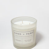 21 oz Sand + Paws Library scented candle in clear jar with wicks and label