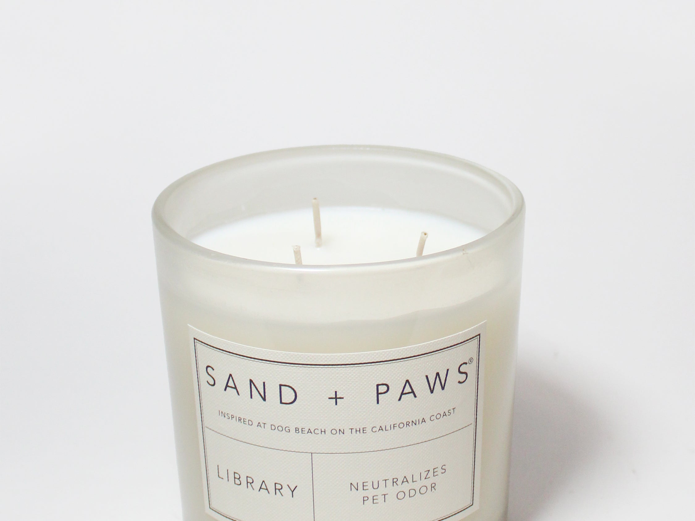 21 oz Sand + Paws Library scented candle in clear jar with wicks and label