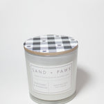 Scented candle jar with plaid paw-print lid and Sand + Paws Mahogany & Teakwood label
