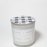 Scented candle jar with plaid paw-print lid and Sand + Paws Mahogany & Teakwood label