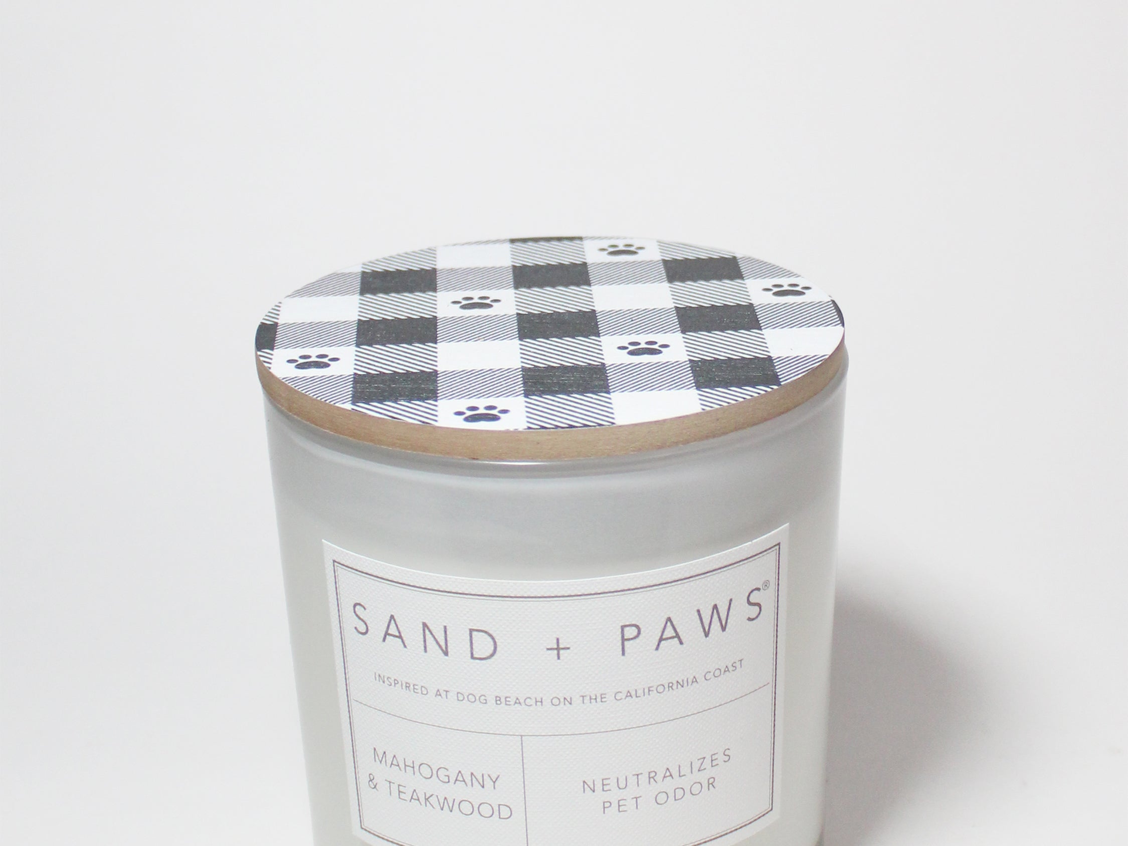 Scented candle jar with plaid paw-print lid and Sand + Paws Mahogany & Teakwood label