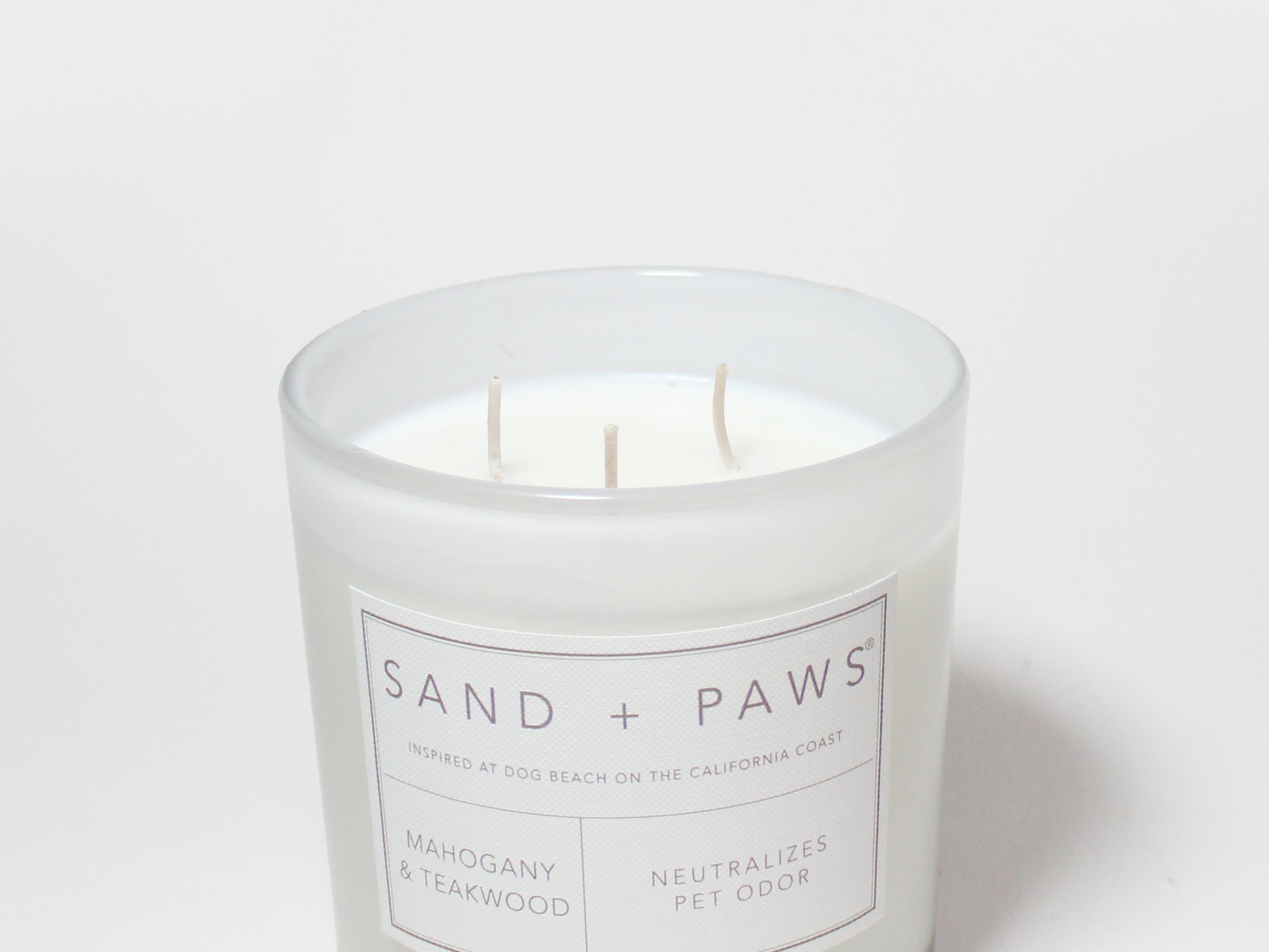 Glass scented candle with Sand + Paws label, Mahogany & Teakwood, and three wicks