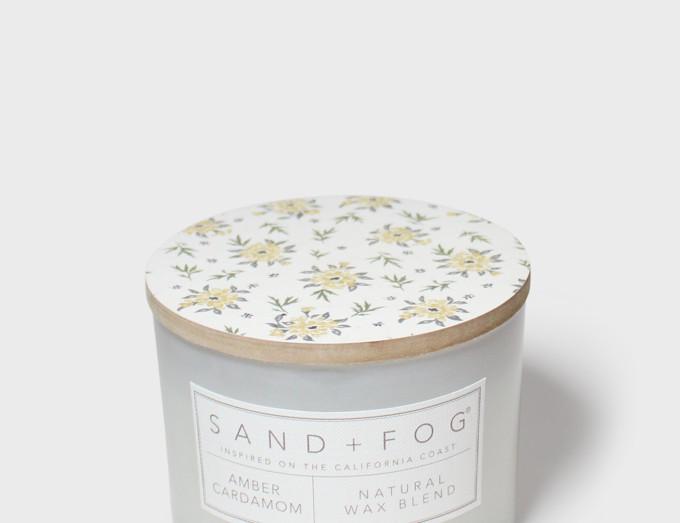 Amber cardamom scented candle jar with floral lid and natural wax blend label