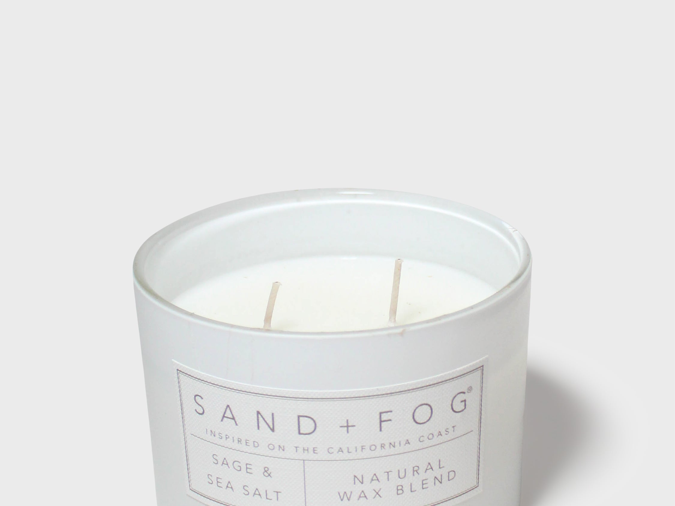 SAND+FOG sage & sea salt scented candle with visible wax and wick in jar