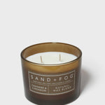 Brown scented candle in glass jar with white wax and SAND+FOG label