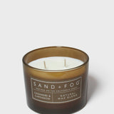 Brown scented candle in glass jar with white wax and SAND+FOG label