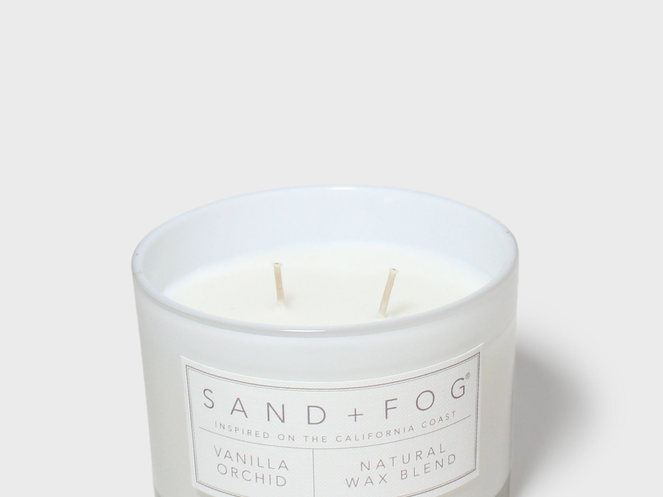 Vanilla orchid scented candle in glass jar with two wicks and centered label