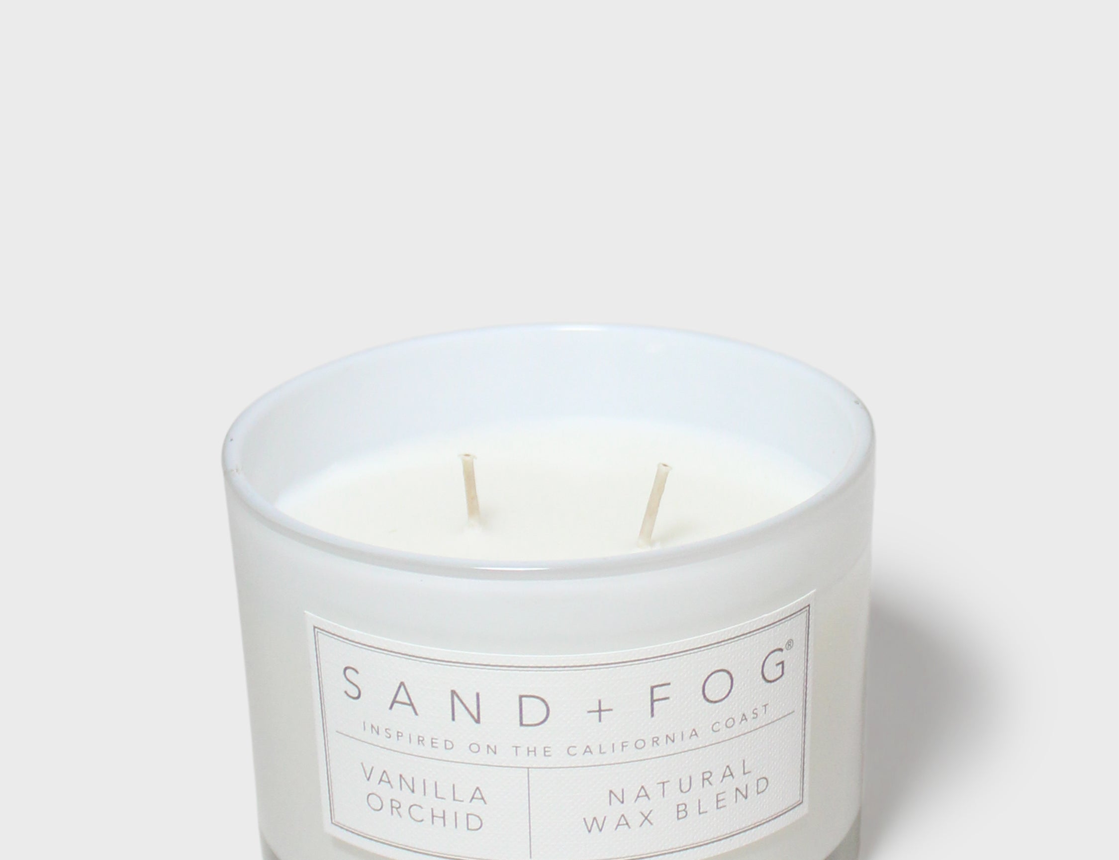 Vanilla orchid scented candle in glass jar with two wicks and centered label