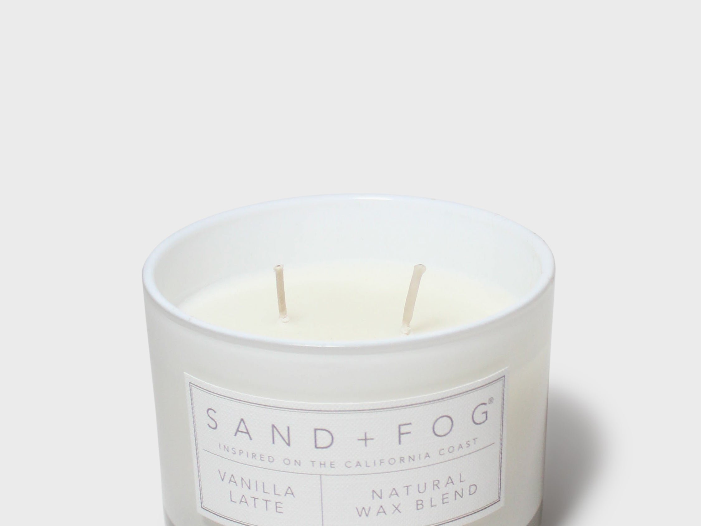 Scented candle in frosted jar with white wax, two wicks, and front label