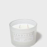 Scented candle in frosted glass jar with two wicks and SAND+FOG Amber & Pear label