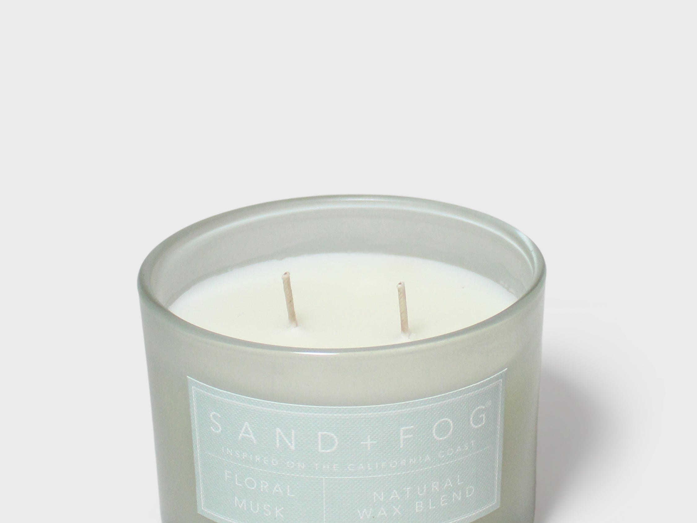 Scented candle jar with pale wax, two wicks, Sand+Fog label