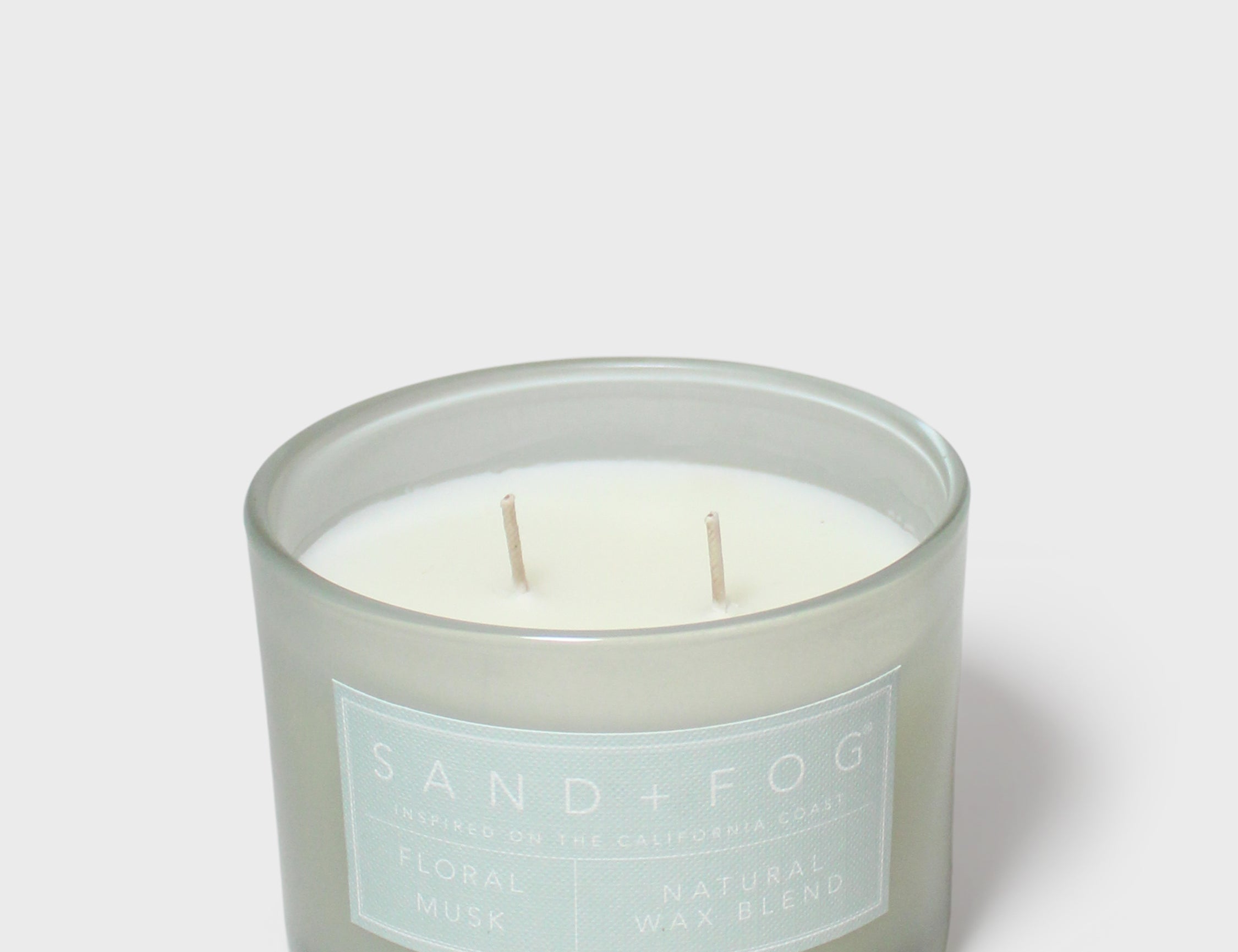 Scented candle jar with pale wax, two wicks, Sand+Fog label