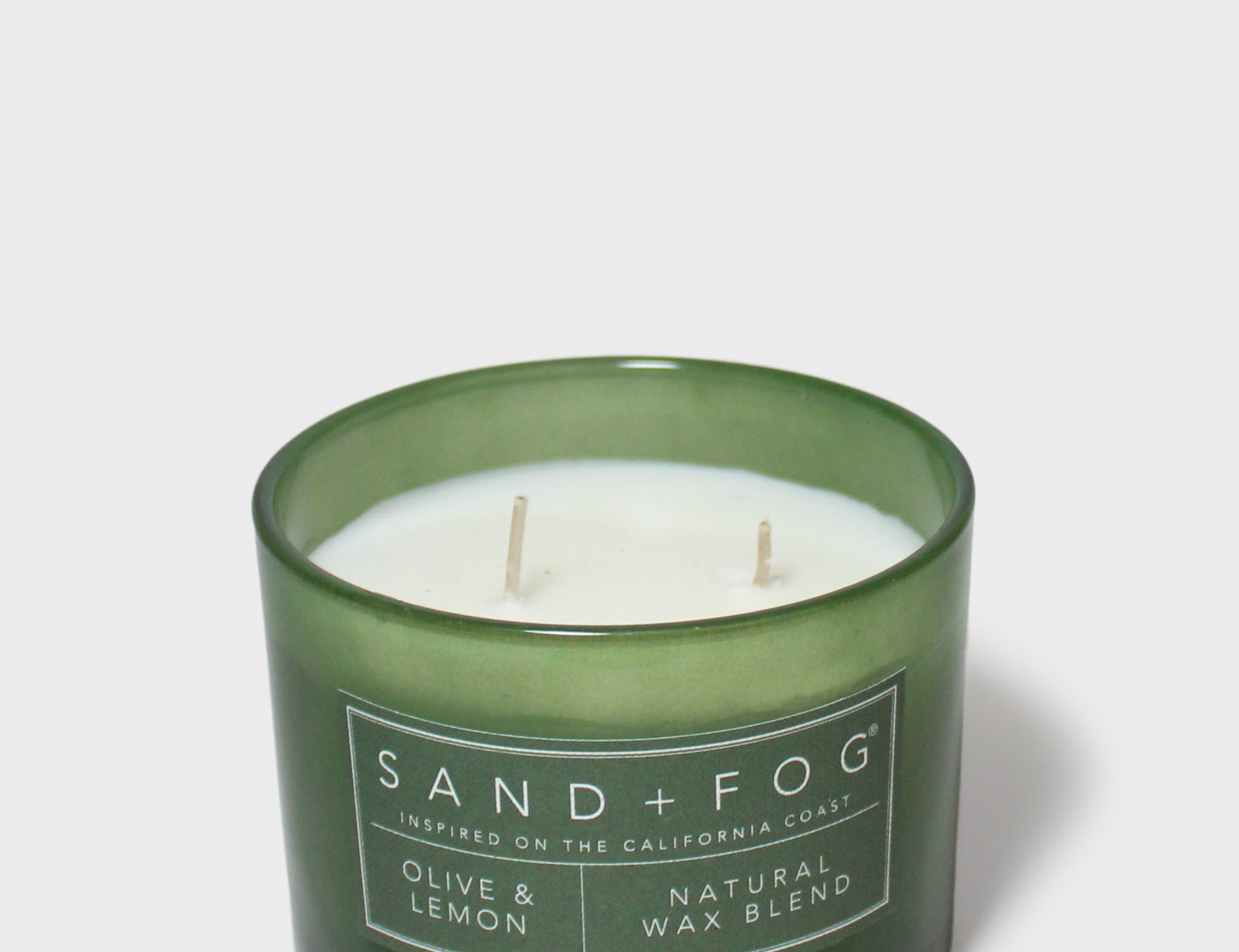 Green glass scented candle with twin wicks and Sand+Fog label