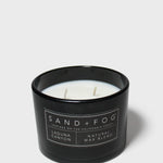 Scented candle in black glass jar with label and visible wax and wick