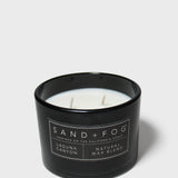 Scented candle in black glass jar with label and visible wax and wick