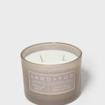 Sand+Fog vanilla scented candle in brown glass jar with white wax and two wicks