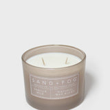 Sand+Fog vanilla scented candle in brown glass jar with white wax and two wicks
