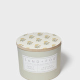 Scented candle with cream floral lid and Sand + Fog Sweet Lemon label