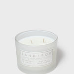 Clear glass jar scented candle with two wicks and Sand + Fog label