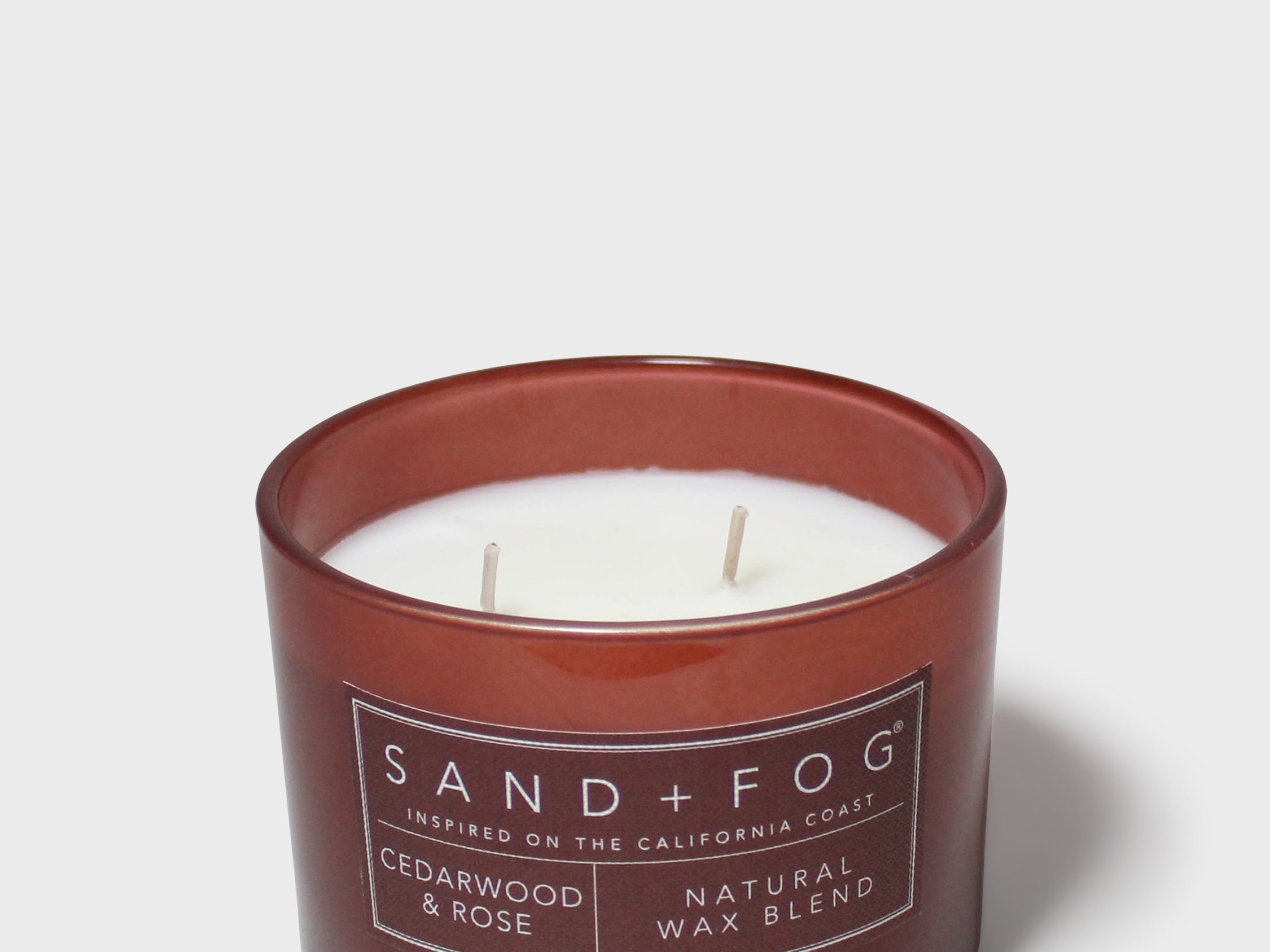SAND+FOG cedarwood & rose scented candle in dark maroon glass jar with two wicks