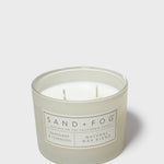 Scented candle in frosted glass jar with Sand+Fog label and two wicks