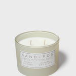 Scented candle in pale gray-green jar, two wicks visible through clear glass