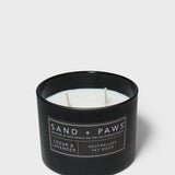 Black candle jar with wick visible and plaid paw label on front