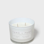 Scented candle in white glass jar with Sand + Paws label and two wicks