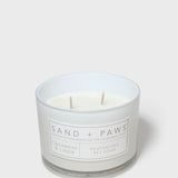 Scented candle in white glass jar with Sand + Paws label and two wicks