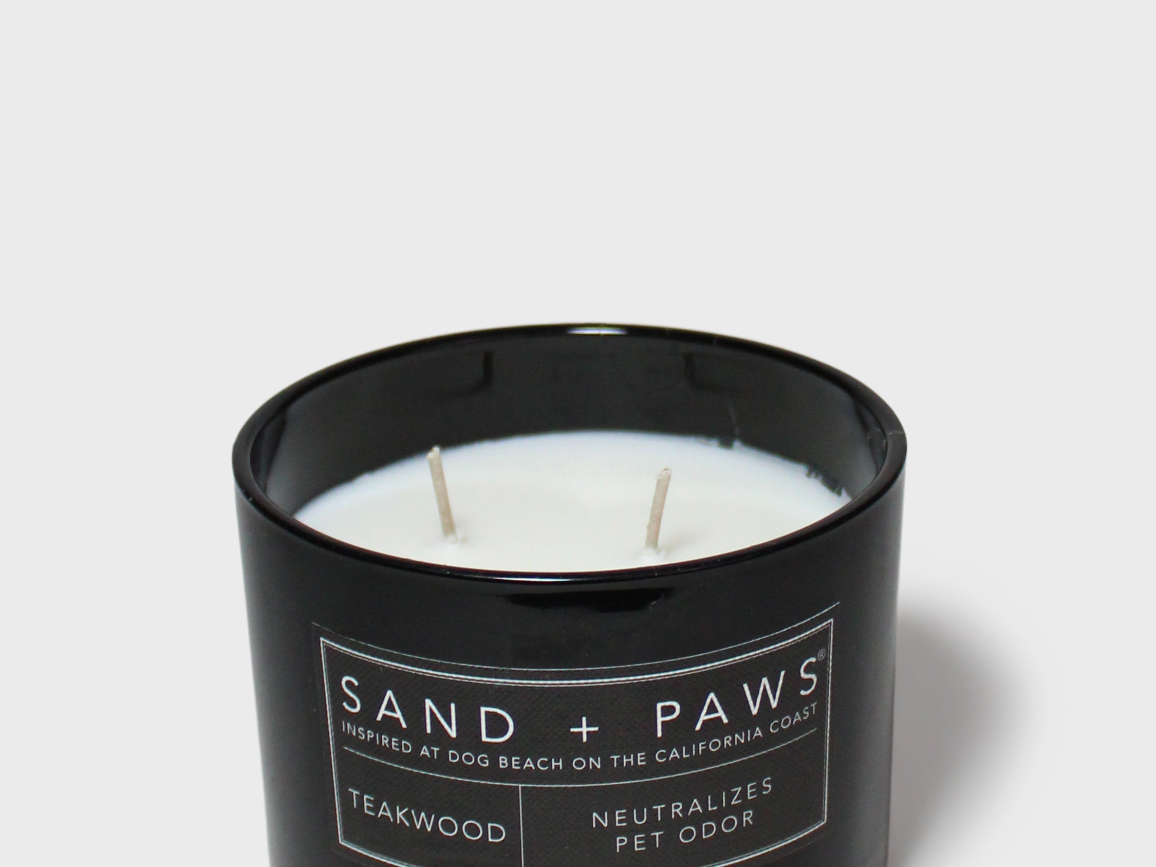 Scented candle in black jar with wicks and Teakwood label on front