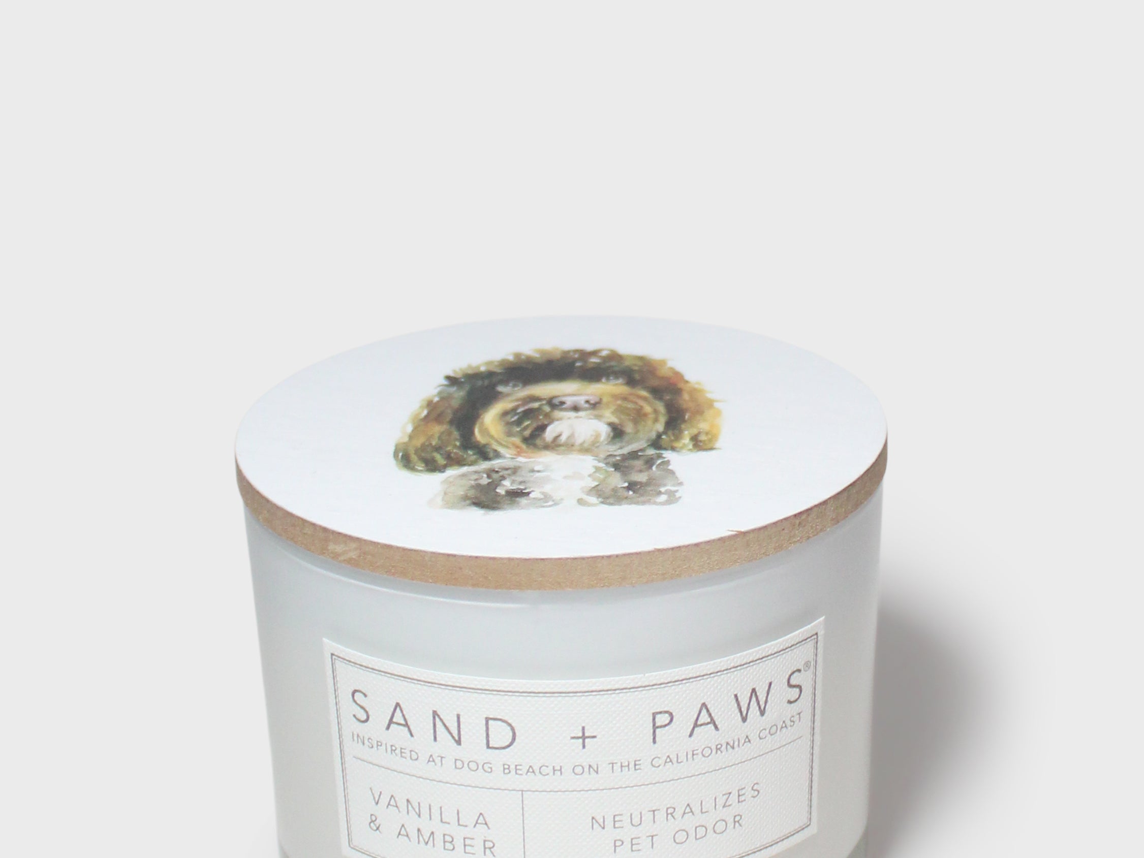 Scented candle jar with dog graphic lid and front label reading Vanilla & Amber