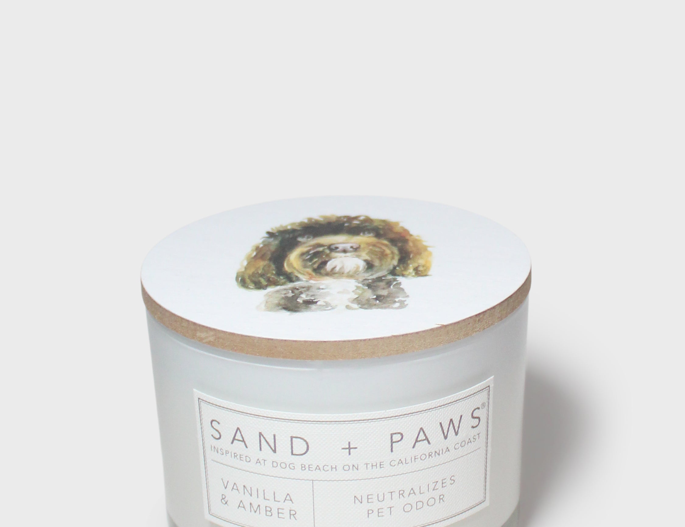 Scented candle jar with dog graphic lid and front label reading Vanilla & Amber