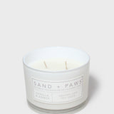 Vanilla & amber scented jar candle with 'Sand + Paws' label and two wicks.