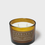 Gold-rim candle jar with white wax and two wicks, labeled Vanilla Sandalwood