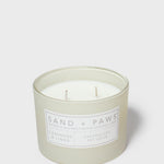 Mint green scented candle in jar with “SAND + PAWS” label and two wicks