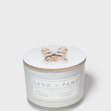 White scented candle with dog portrait lid and Sand + Paws label on jar