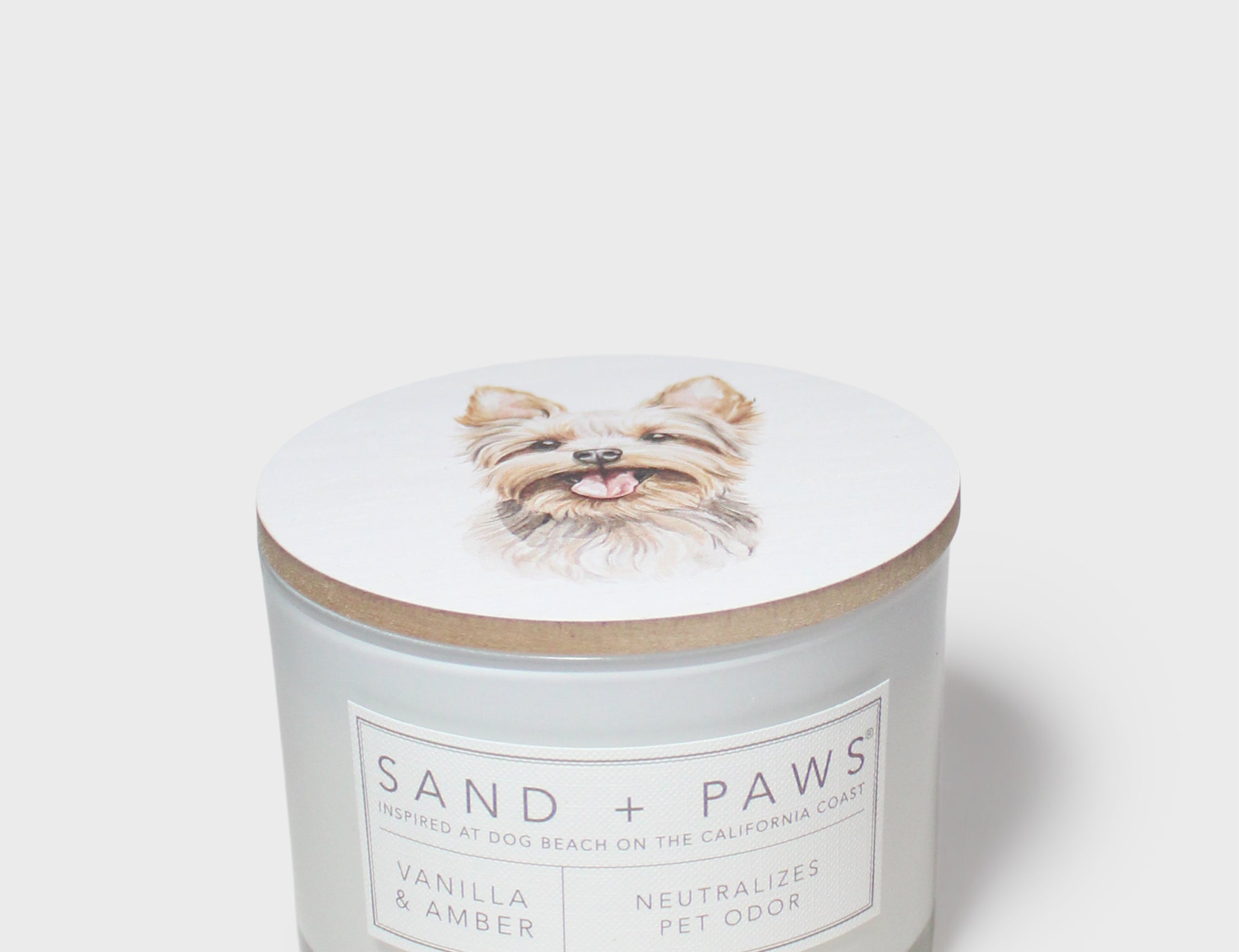 White scented candle with dog portrait lid and Sand + Paws label on jar