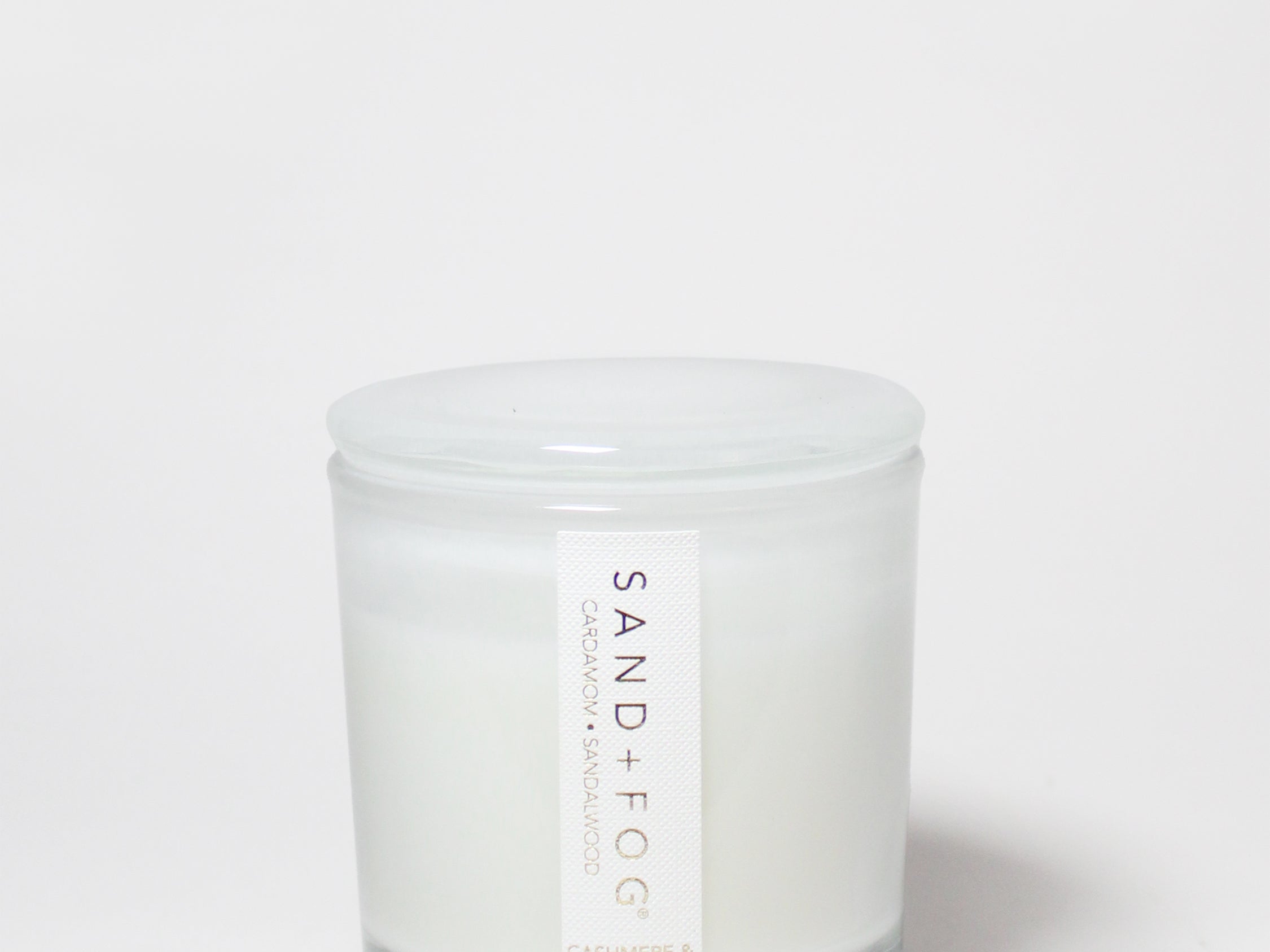 Cashmere & Cardamom candle in a clear glass jar with a white lid and white wax.