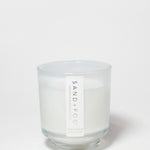 Cashmere & Cardamom scented candle in a clear glass jar with a white wax fill and label.