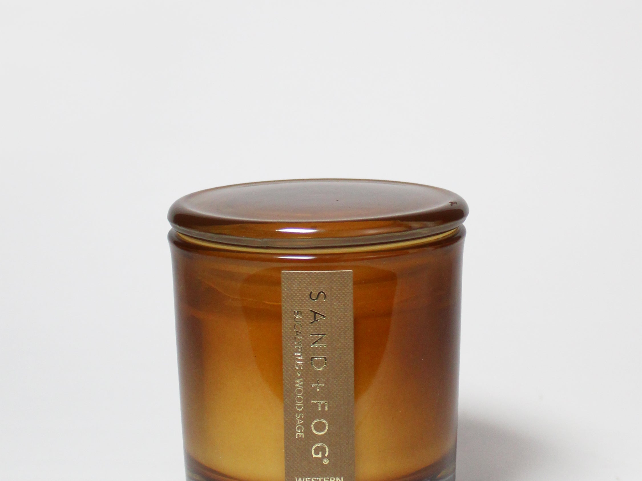 Western Oak 8 oz scented candle in an amber glass jar with its matching lid on.