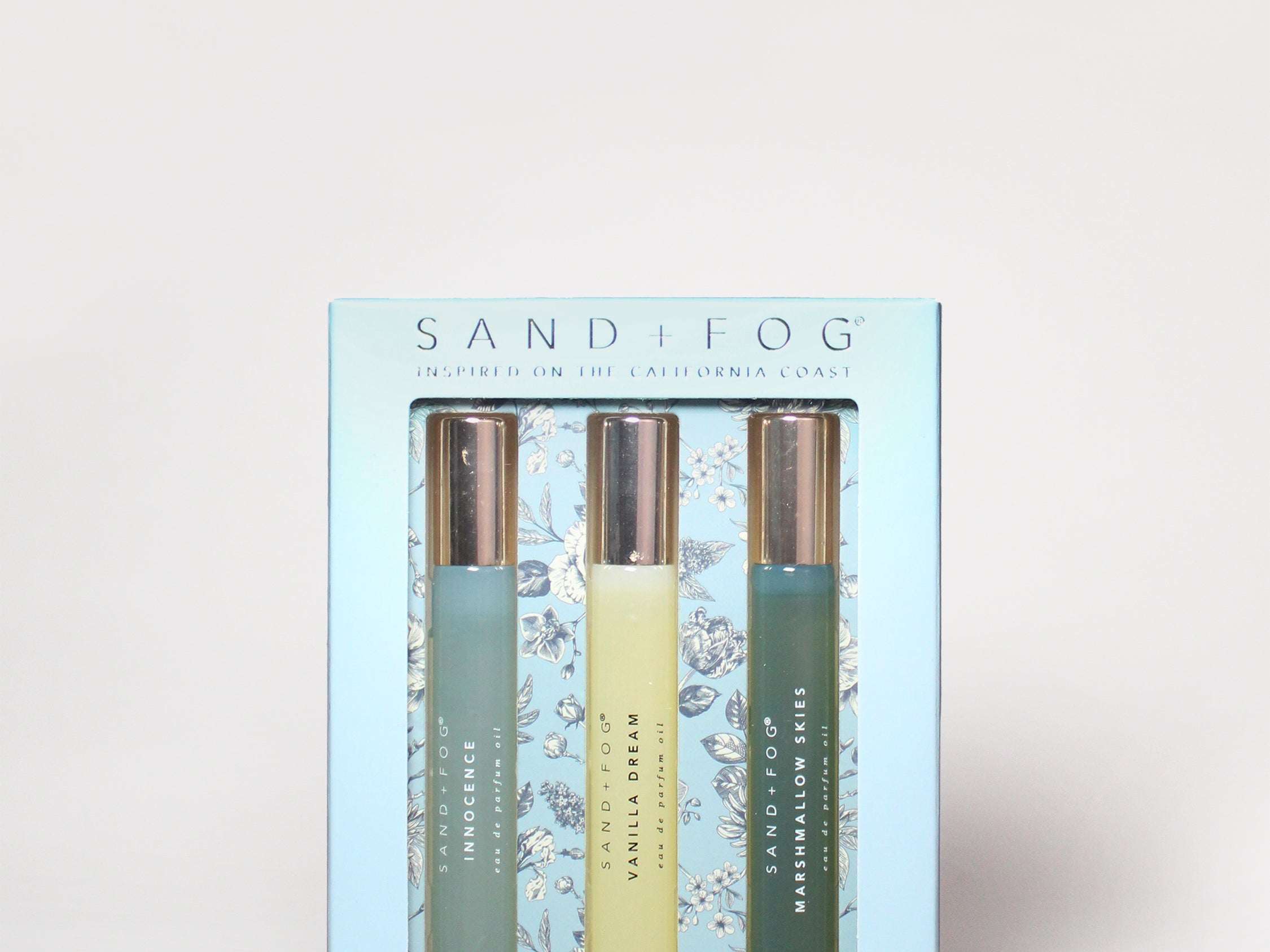 Light blue perfume oil set box with three roller bottles and gold/green labels