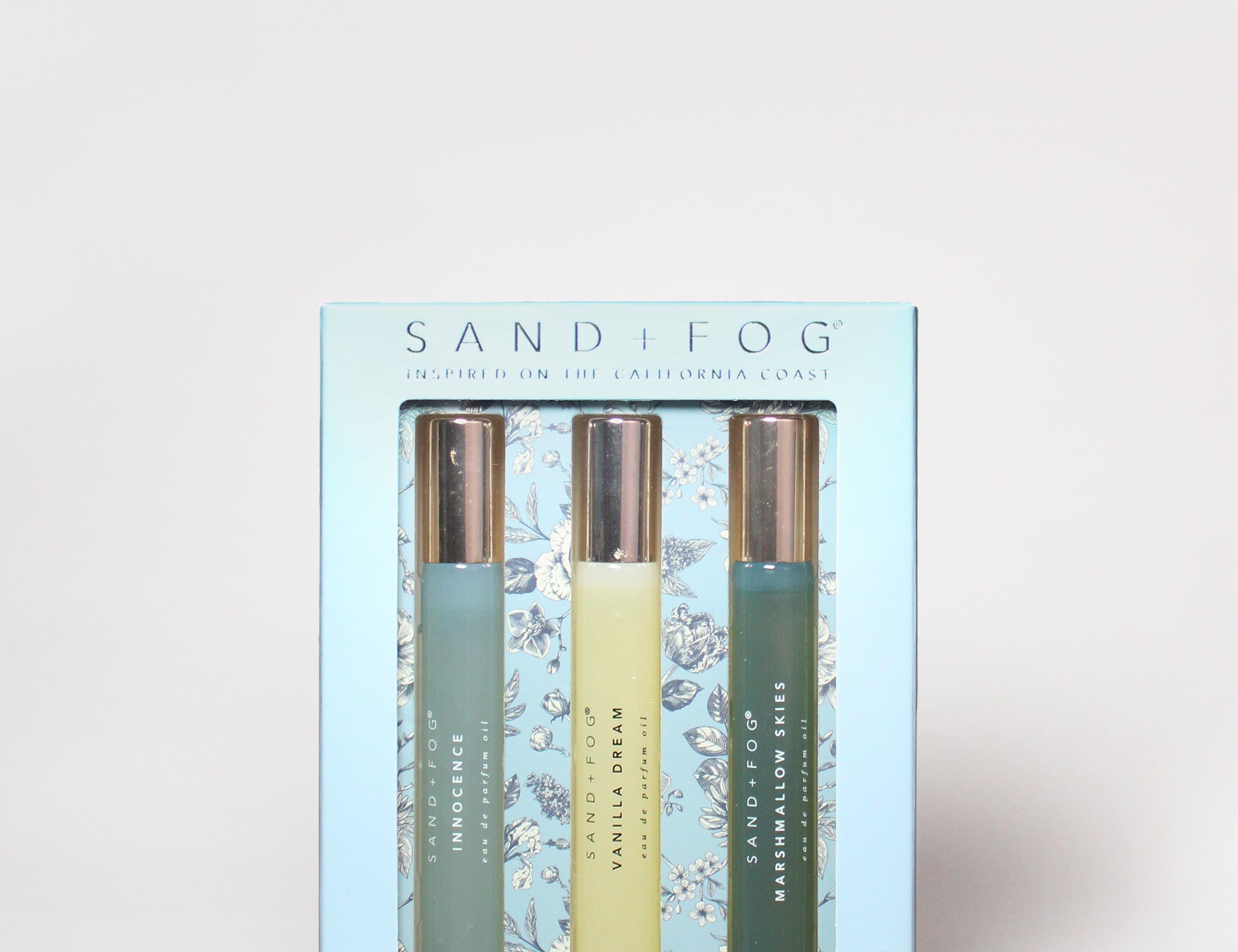 Light blue perfume oil set box with three roller bottles and gold/green labels