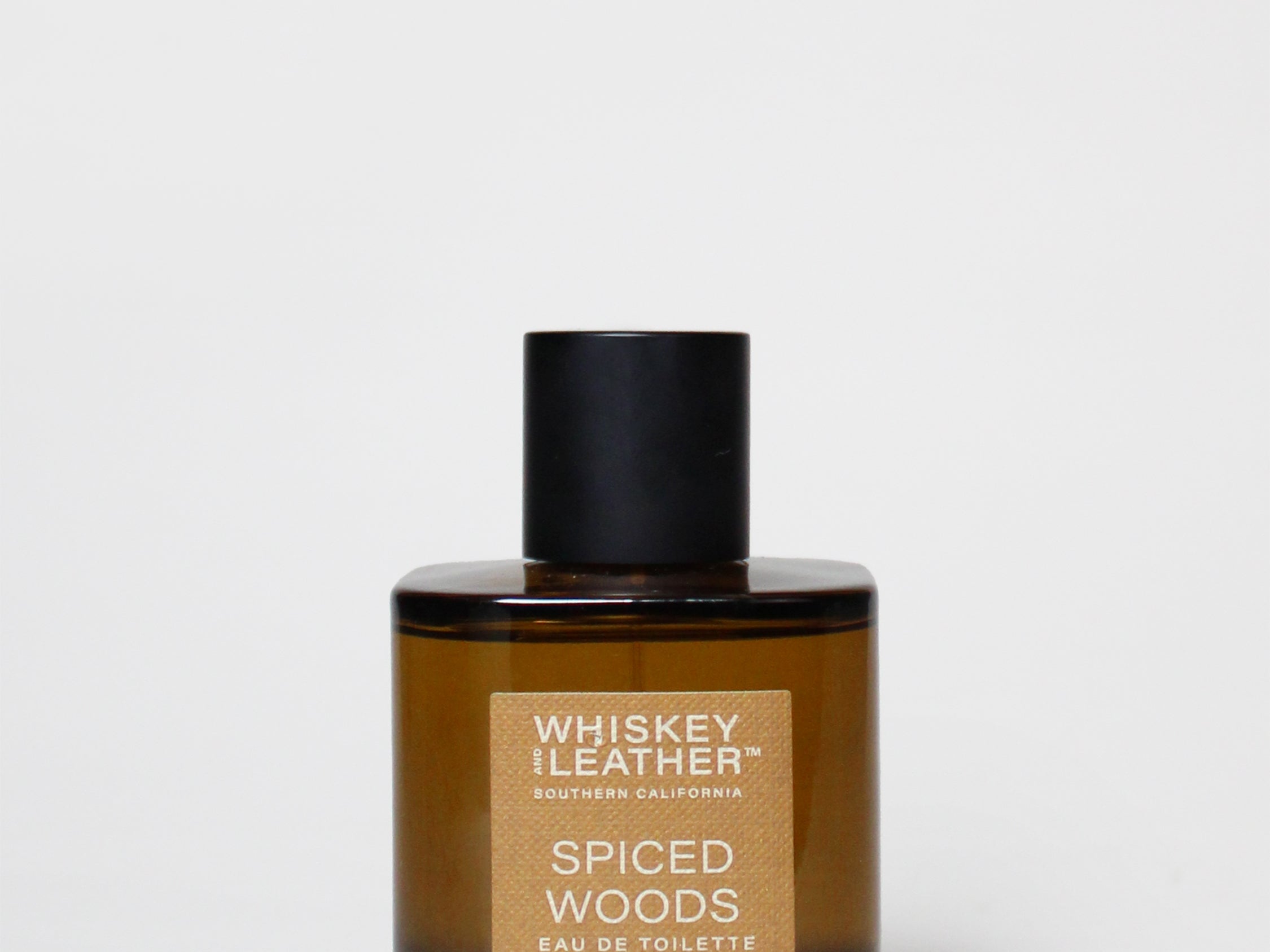 Amber cologne bottle with black cap and Spiced Woods label