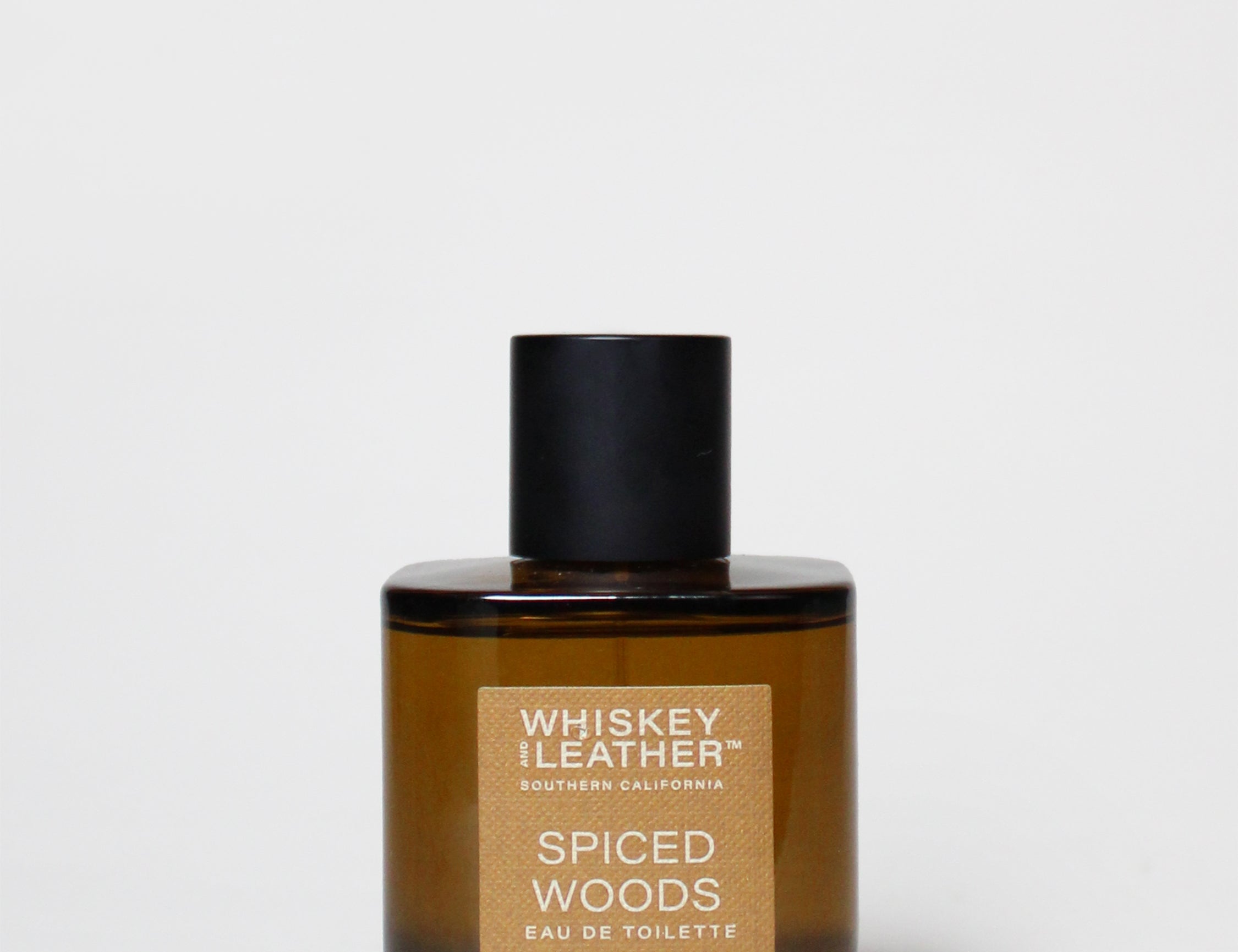 Amber cologne bottle with black cap and Spiced Woods label