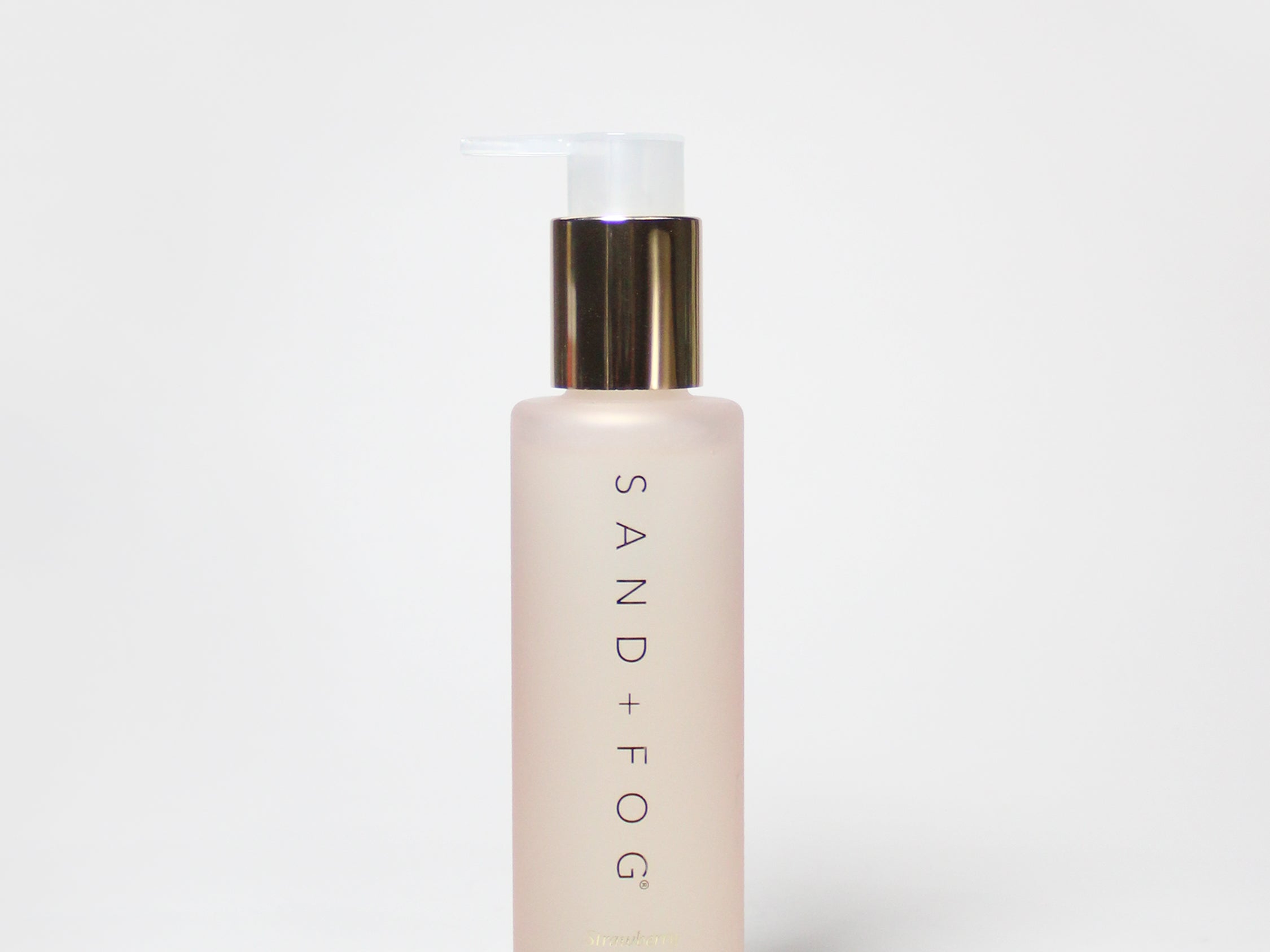 Strawberry body oil bottle with gold pump, pink liquid