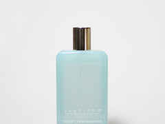 Light blue room spray bottle with gold cap, labeled Violet Sandalwood