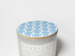 12 oz scented candle with frosted jar and Sand+Fog label, blue seashell lid