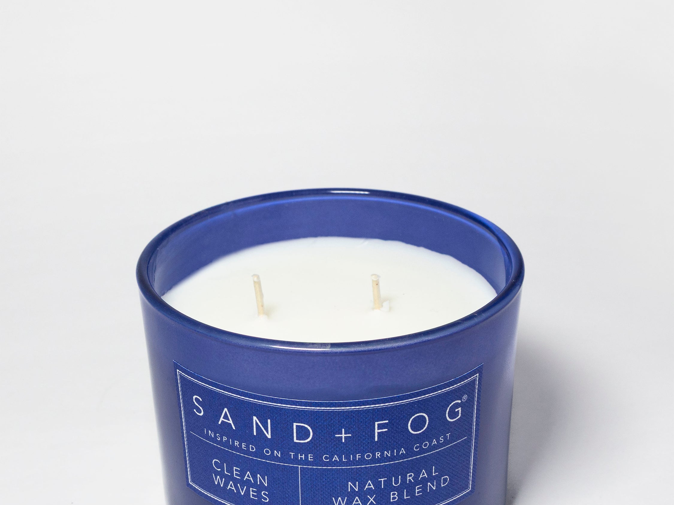 Open Clean Waves candle in a navy glass jar with white wax and two wicks